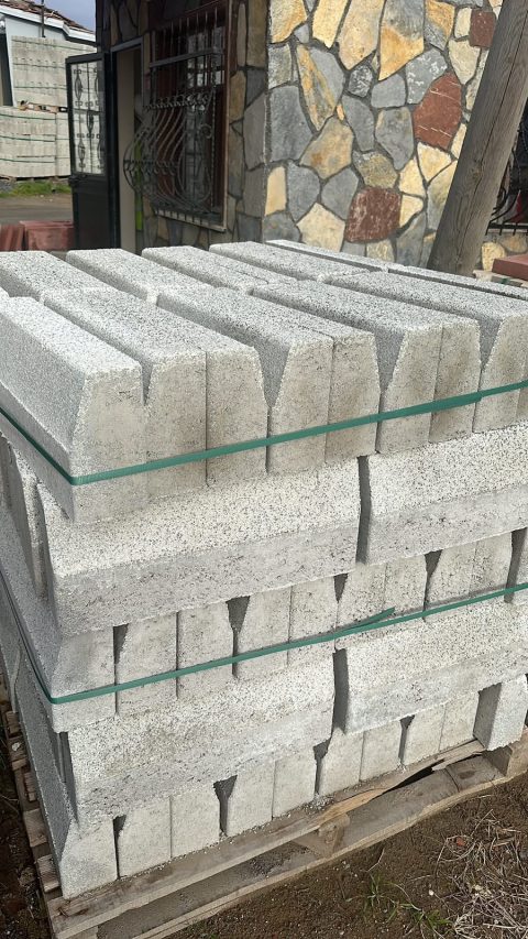 Paletlenmiş beton bordürler ve arkada doğal taş duvar