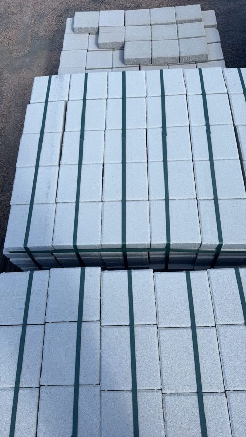 Stok sahasında paletlenmiş gri beton bordür taşları